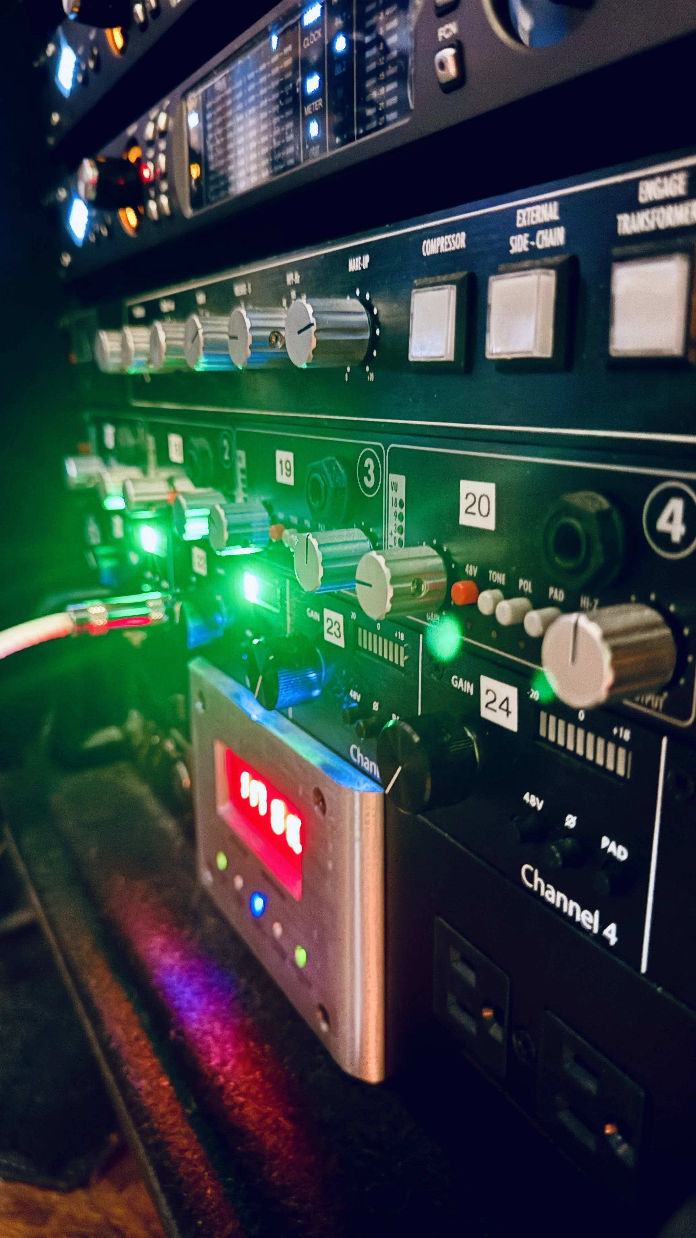 Close-up of an audio mixer with illuminated knobs, switches, and LED indicators, used in music production or sound engineering.