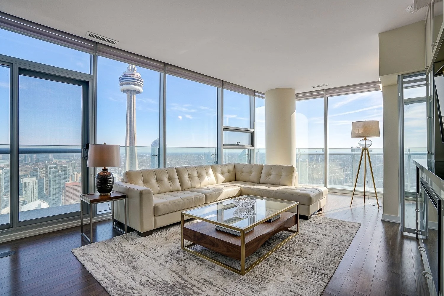 Luxury corner living room with floor-to-ceiling windows showcasing breathtaking CN Tower and Toronto skyline views, complemented by abundant natural light and an elegant open-concept design.