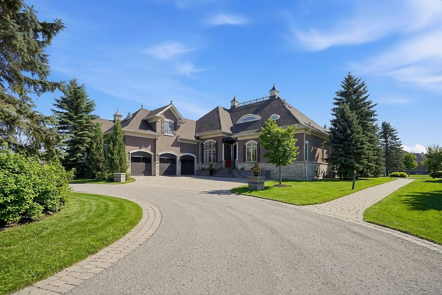 Grand luxury estate featuring elegant architecture, a sweeping circular driveway, meticulously landscaped grounds, mature trees, and exceptional curb appeal on a prestigious oversized lot.