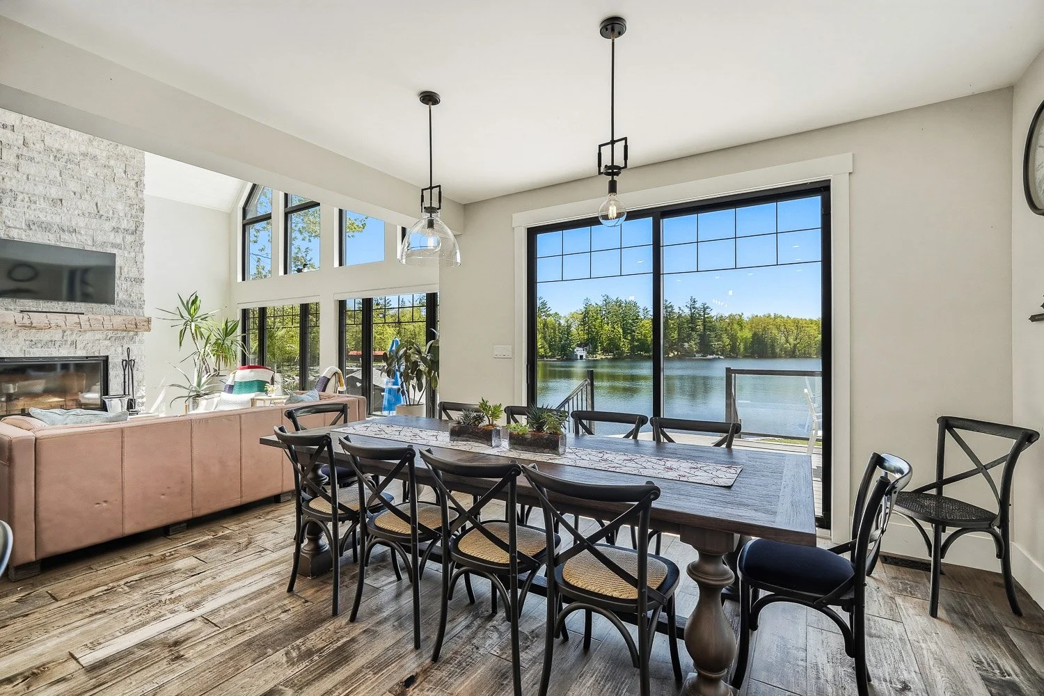 Waterfront dining area with expansive lake views, oversized sliding glass doors, and an open-concept layout that seamlessly connects indoor living with the outdoor shoreline.