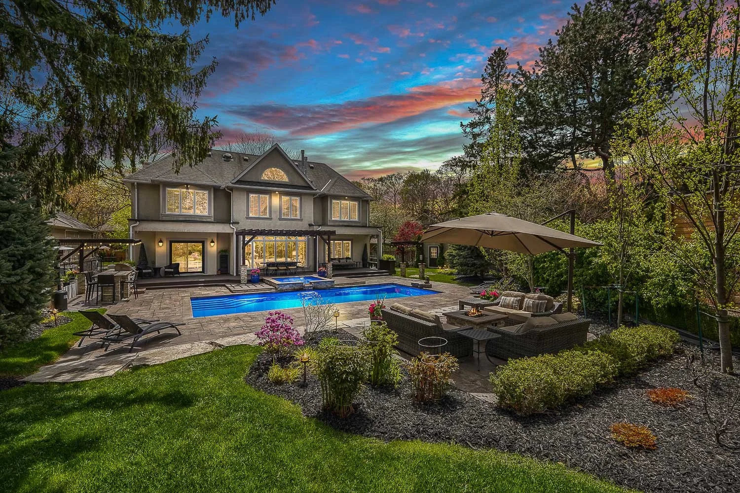 Luxury backyard with swimming pool, landscaped gardens and outdoor lounge at twilight