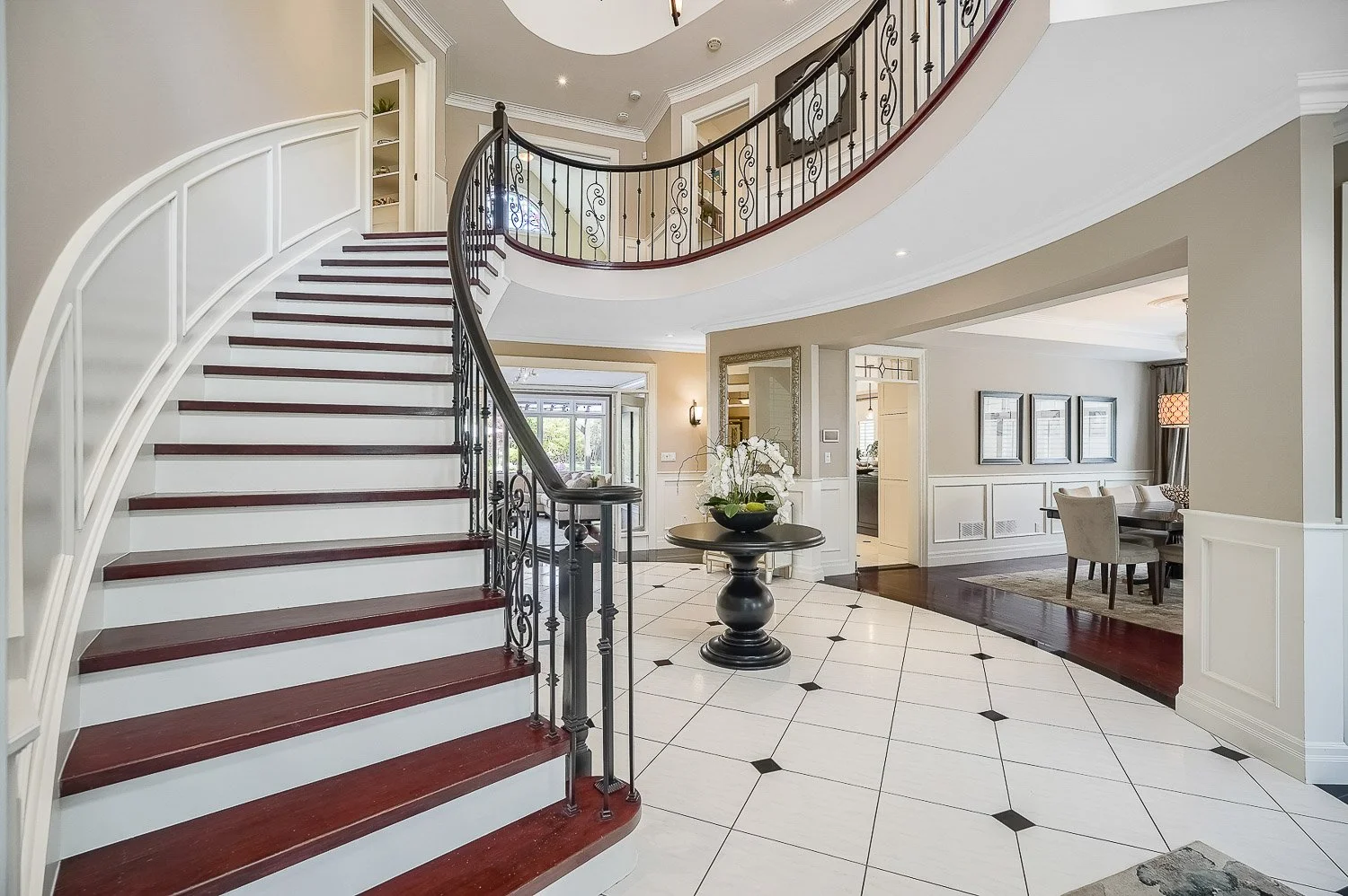 Grand two-storey foyer featuring a sweeping curved staircase, elegant wrought-iron railings, and an impressive open layout that creates a striking first impression
