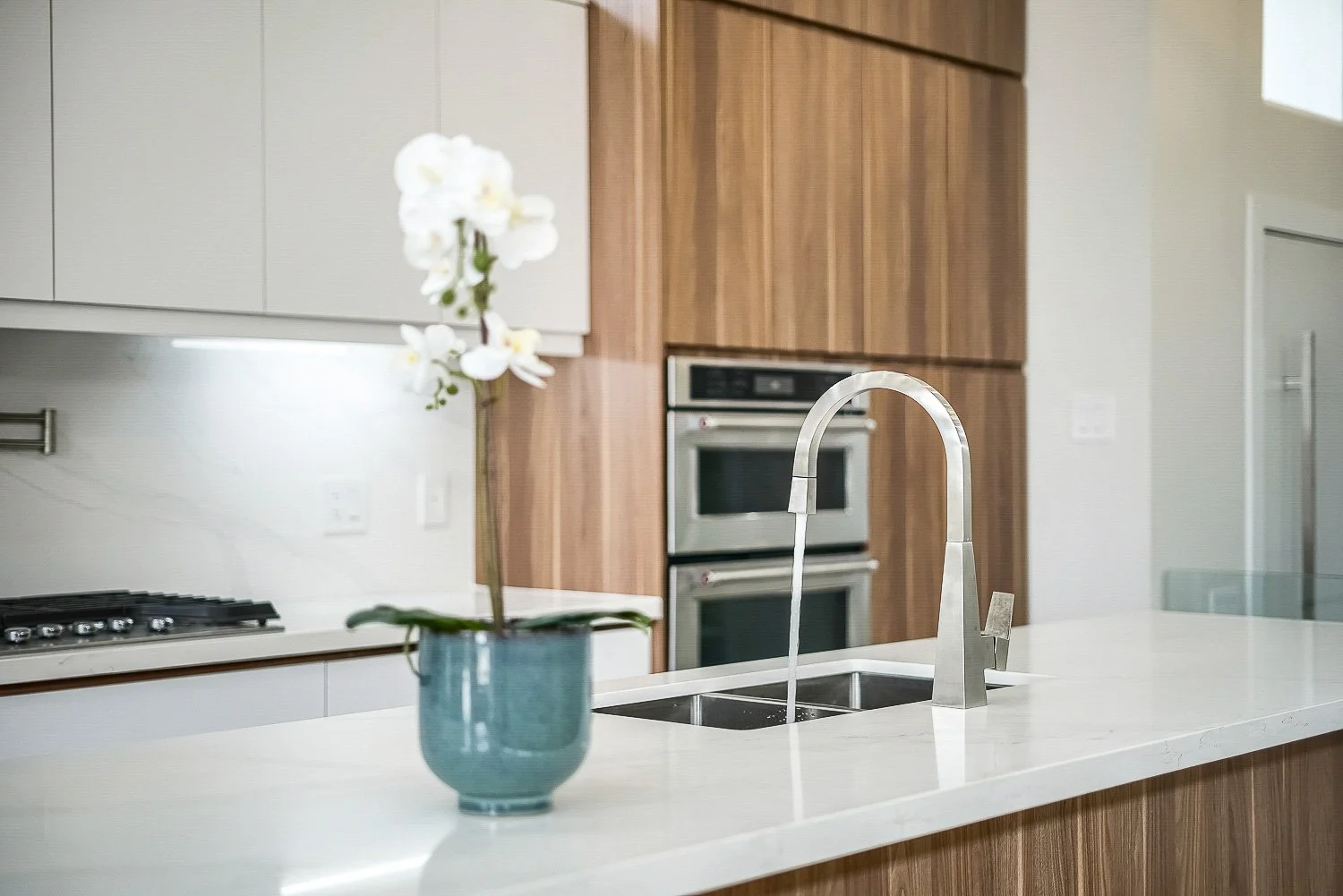 Modern kitchen with quartz waterfall island, built-in appliances and minimalist wood cabinetry