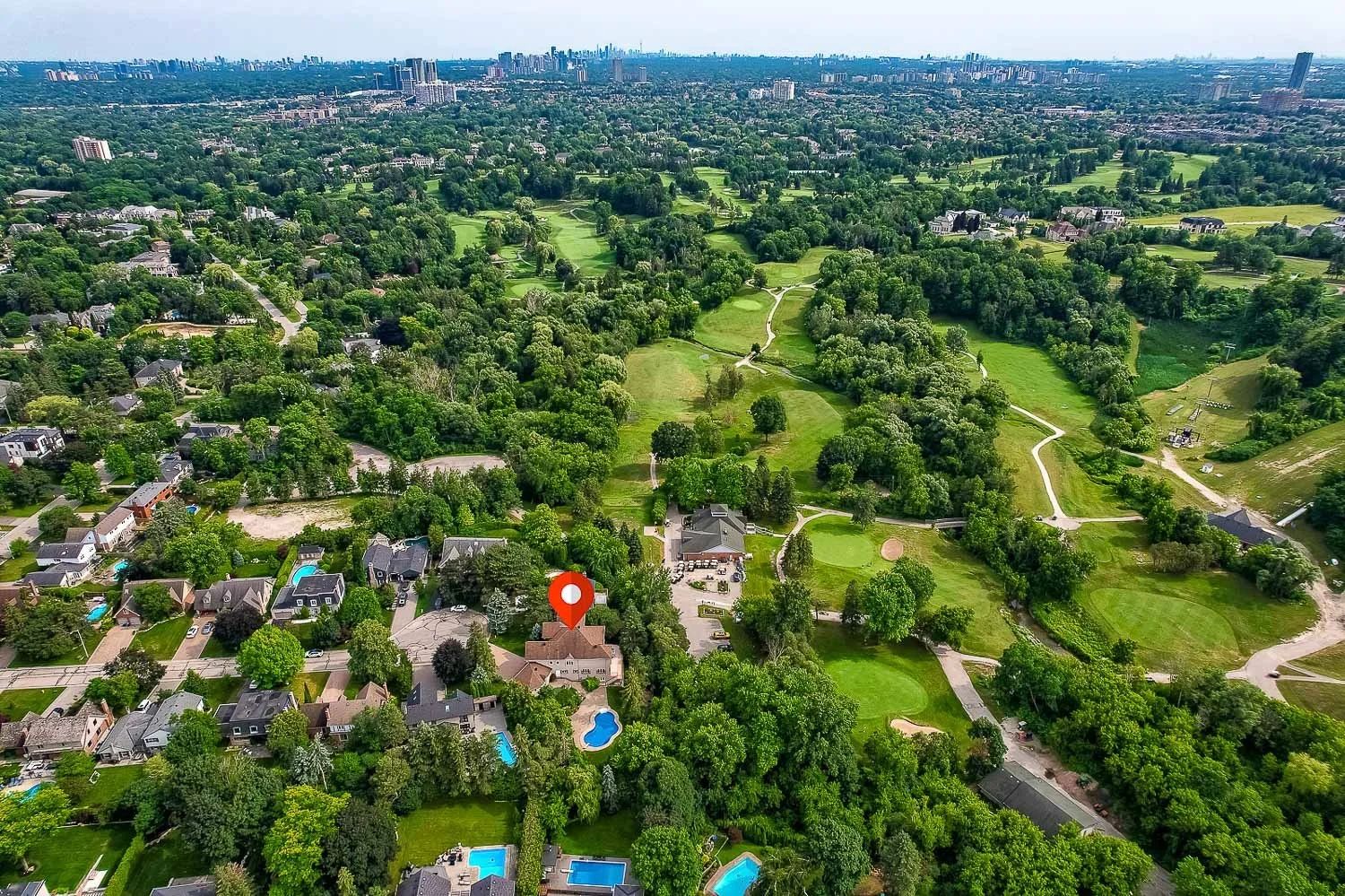 Aerial view of luxury home backing onto a championship golf course surrounded by mature trees and upscale neighbourhood