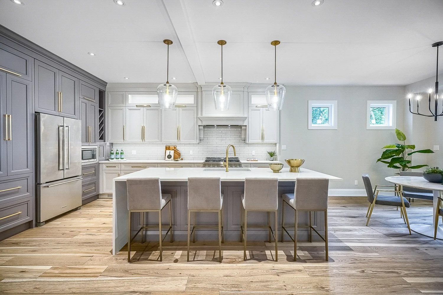 Bright designer kitchen with full-height cabinetry, an oversized quartz island, elegant pendant lighting, and an open layout perfect for entertaining and everyday living