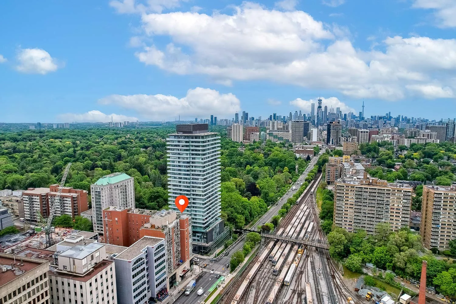 Aerial view highlighting a condominium building with Toronto skyline and surrounding neighbourhood