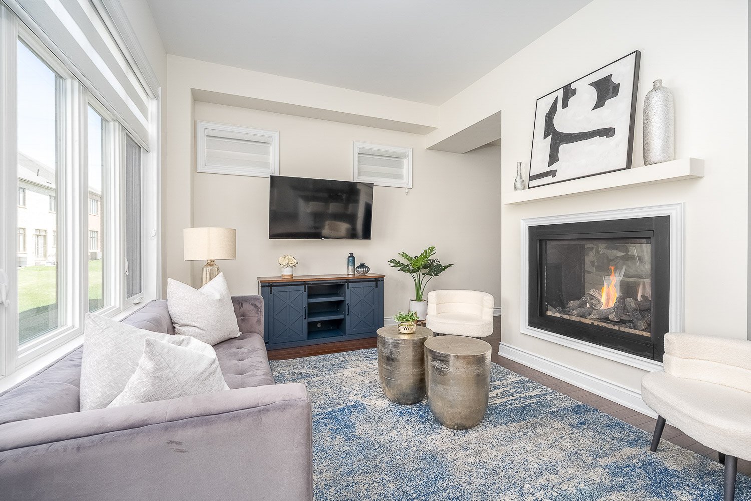 Cozy family room featuring a modern gas fireplace, oversized windows, and comfortable seating, creating a warm and inviting space for everyday living