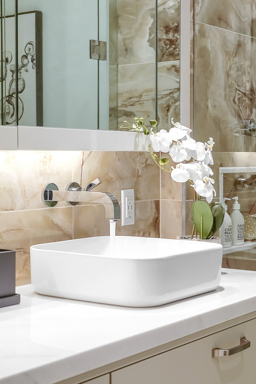 Modern bathroom vanity with vessel sink, floating faucet, marble-look tile and glass shower