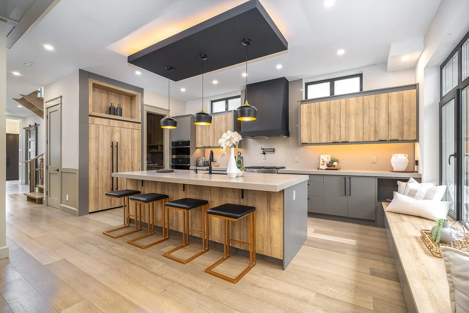 Modern chef-inspired kitchen with a large waterfall island, custom wood cabinetry, designer pendant lighting, and premium finishes, professionally photographed for a Toronto real estate listing.