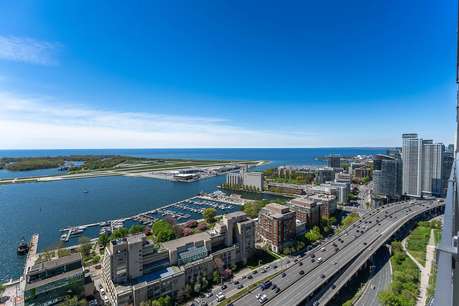 Panoramic skyline view overlooking Lake Ontario, Toronto Islands, Billy Bishop Airport, and Toronto waterfront from a luxury downtown condominium.
