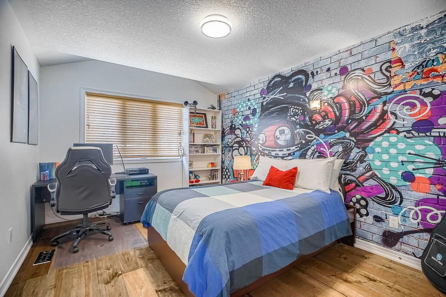 Stylish secondary bedroom with a built-in workspace, bold feature wall mural, and contemporary finishes, offering a functional space for both rest and productivity