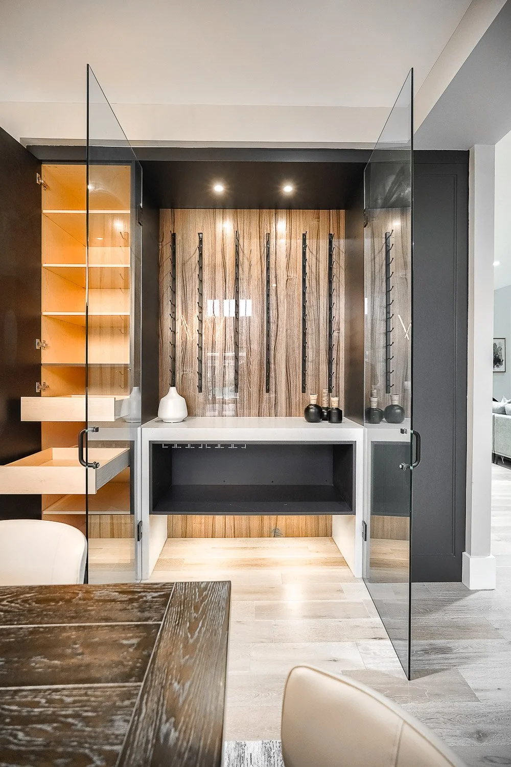 Built-in glass wine display cabinet with custom wood shelving and modern interior design