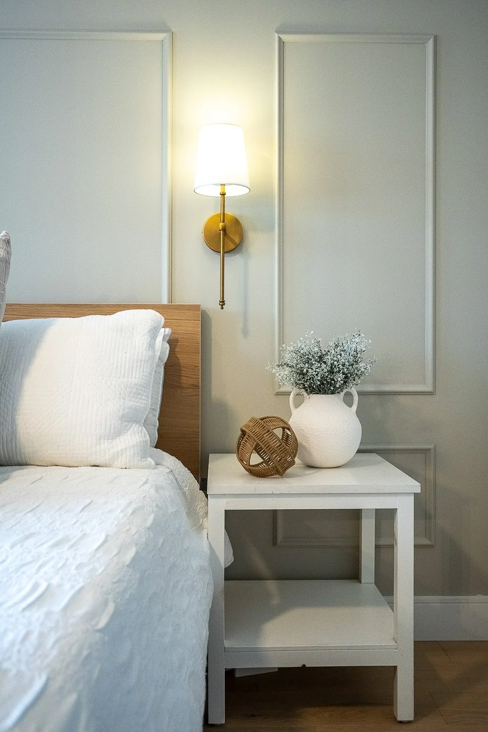 Modern bedroom nightstand with decorative vase, wall sconce and elegant panel moulding
