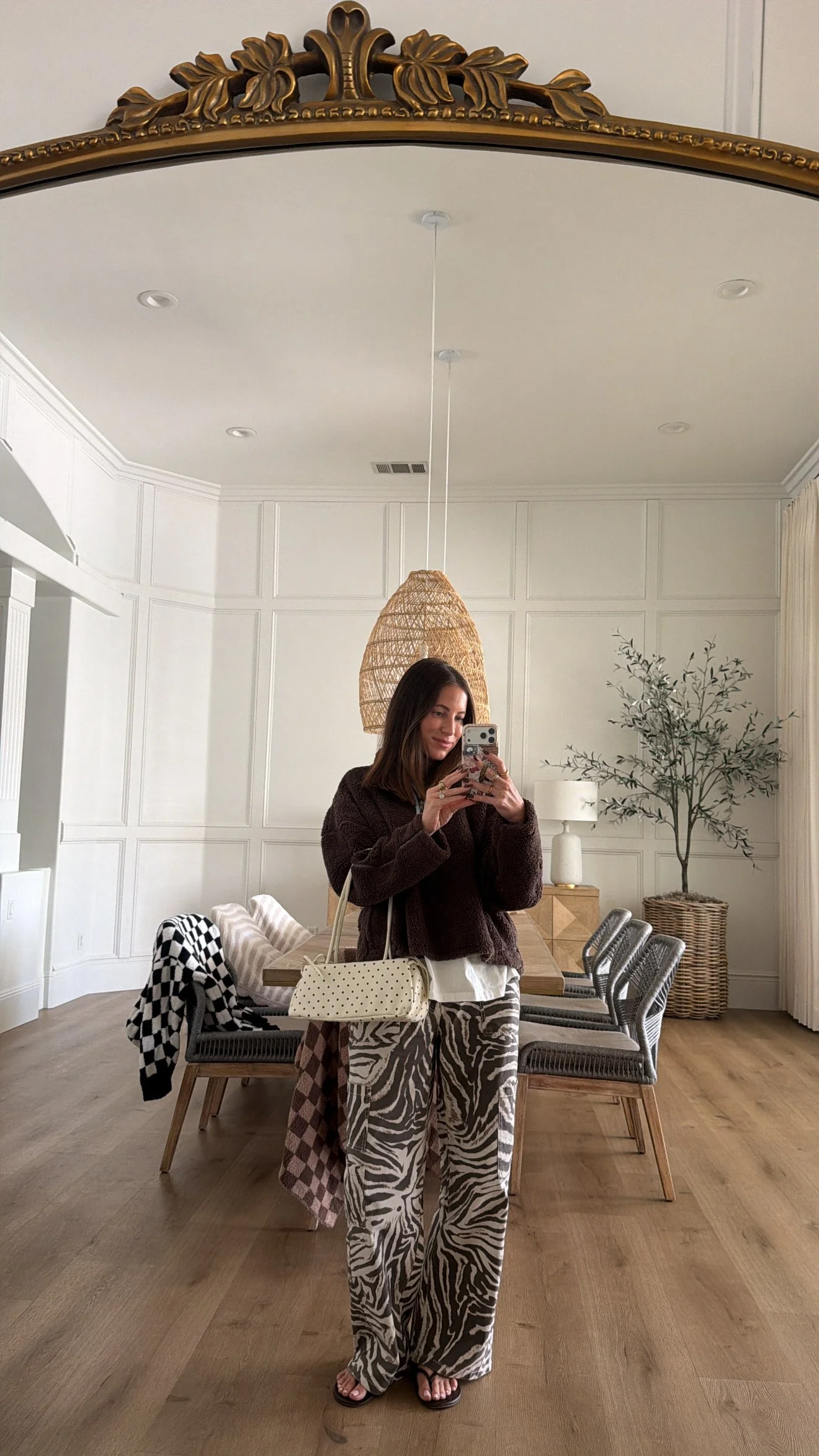 Krista taking a outfit photo wearing a sherpa pullover, zebra pants and flipflops.