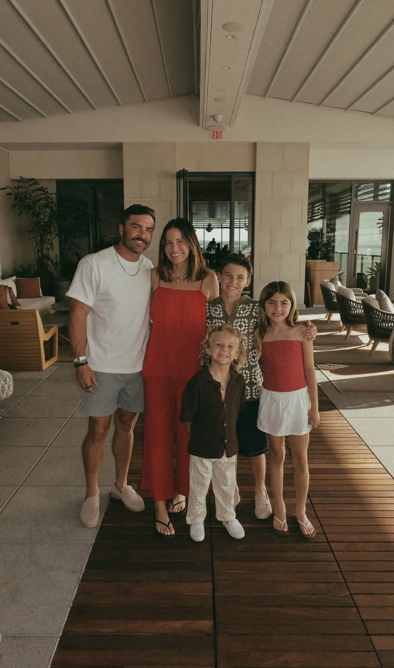 Family of five posing together in indoor/outdoor resort space.