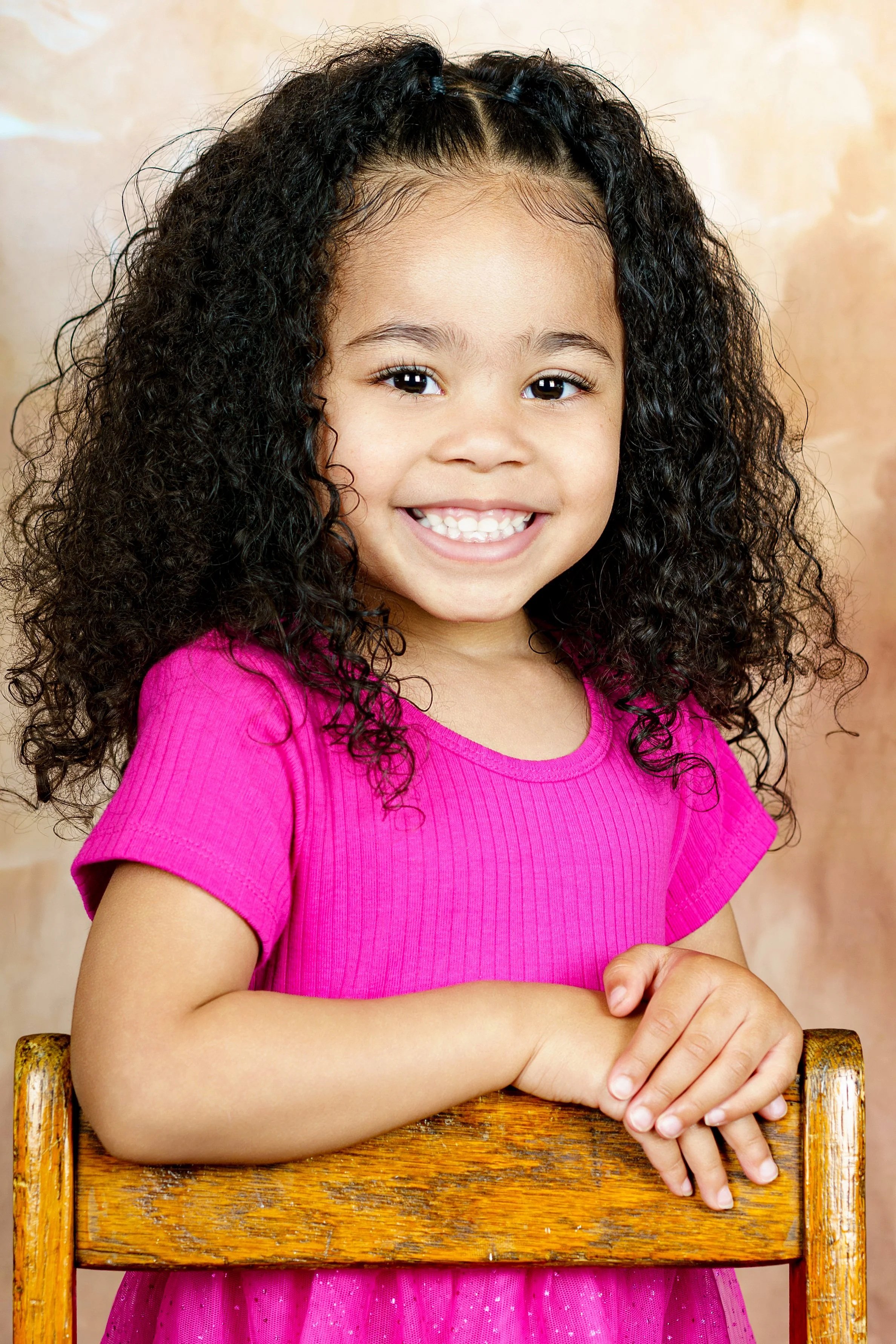 Child smiling in a finished Picture Day portrait against a warm neutral backdrop