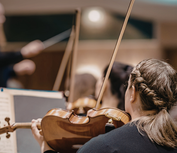 a young student playing violin in an ensemble at an events night