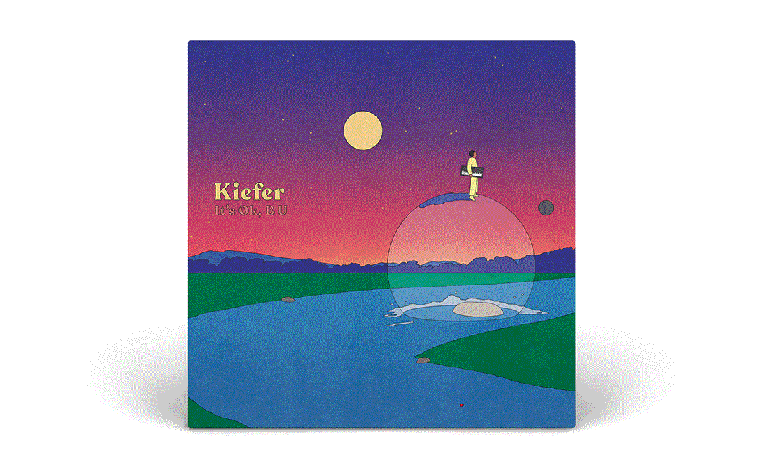 Album cover art with a surreal landscape of a river, green hills, mountains, and a colorful sky with a full moon and stars. A person stands on a small sphere, holding a briefcase, with a transparent bubble around them. The text reads 'Kiefer It's OK, B U'.