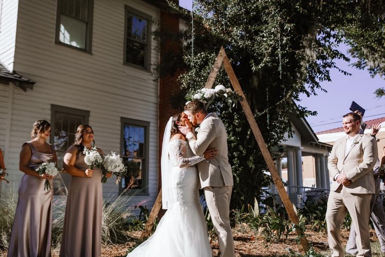 Couple kissing under the wood arbor beside the house