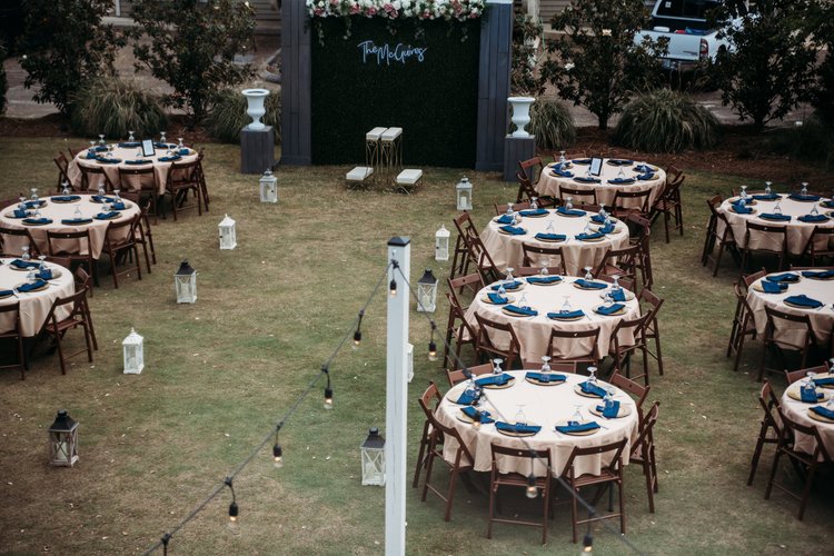 Reception tables lit with lanterns on the lawn at night