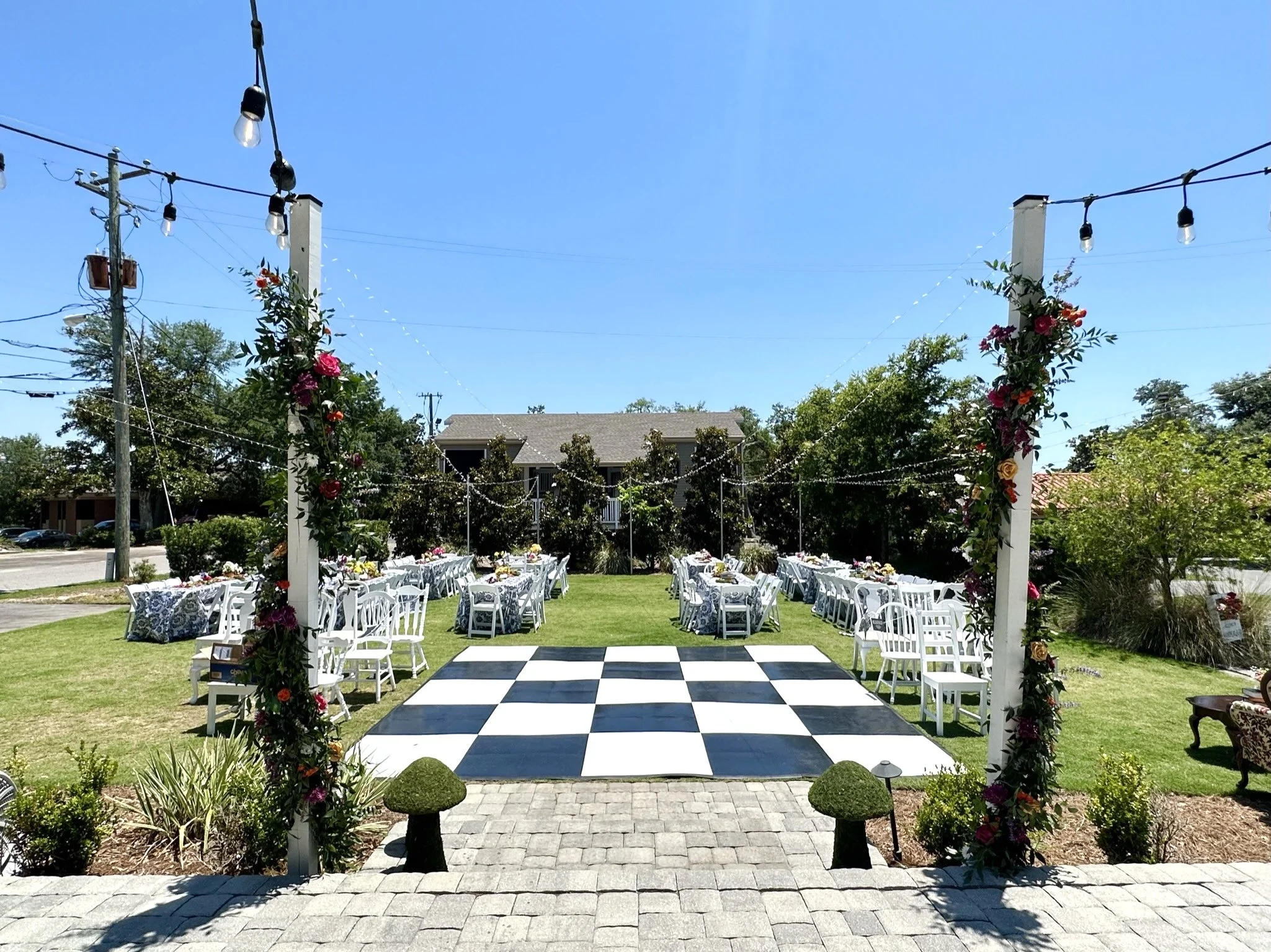 Outdoor wedding reception on the lawn at The Sapp House with a checkered dance floor and floral columns