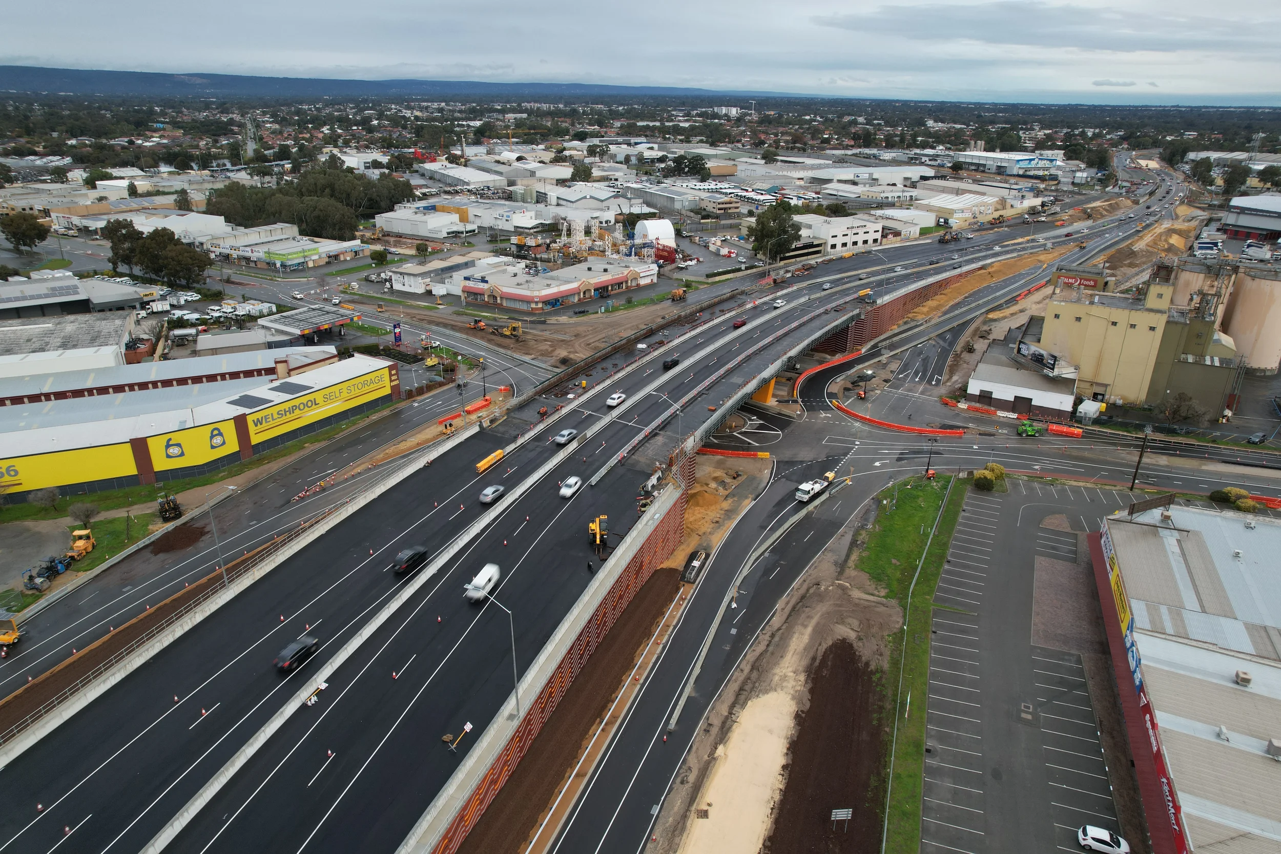 Test and Tag Welshpool: Aerial view of a highway under construction with multiple lanes, overpasses, and surrounding commercial buildings in an urban area.