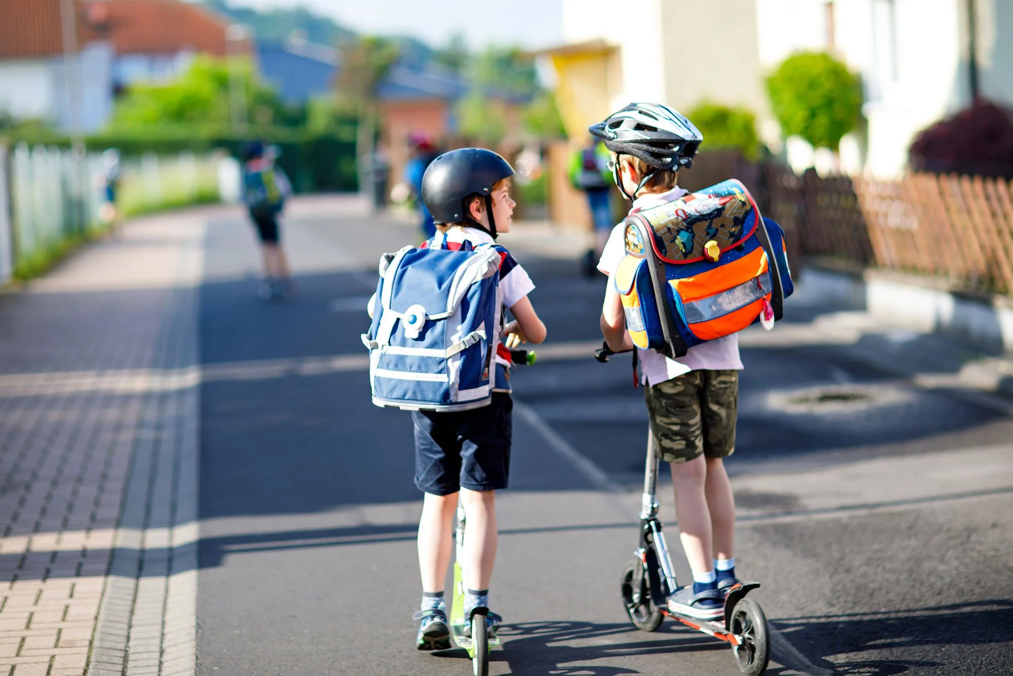Two young children on scooters in the road