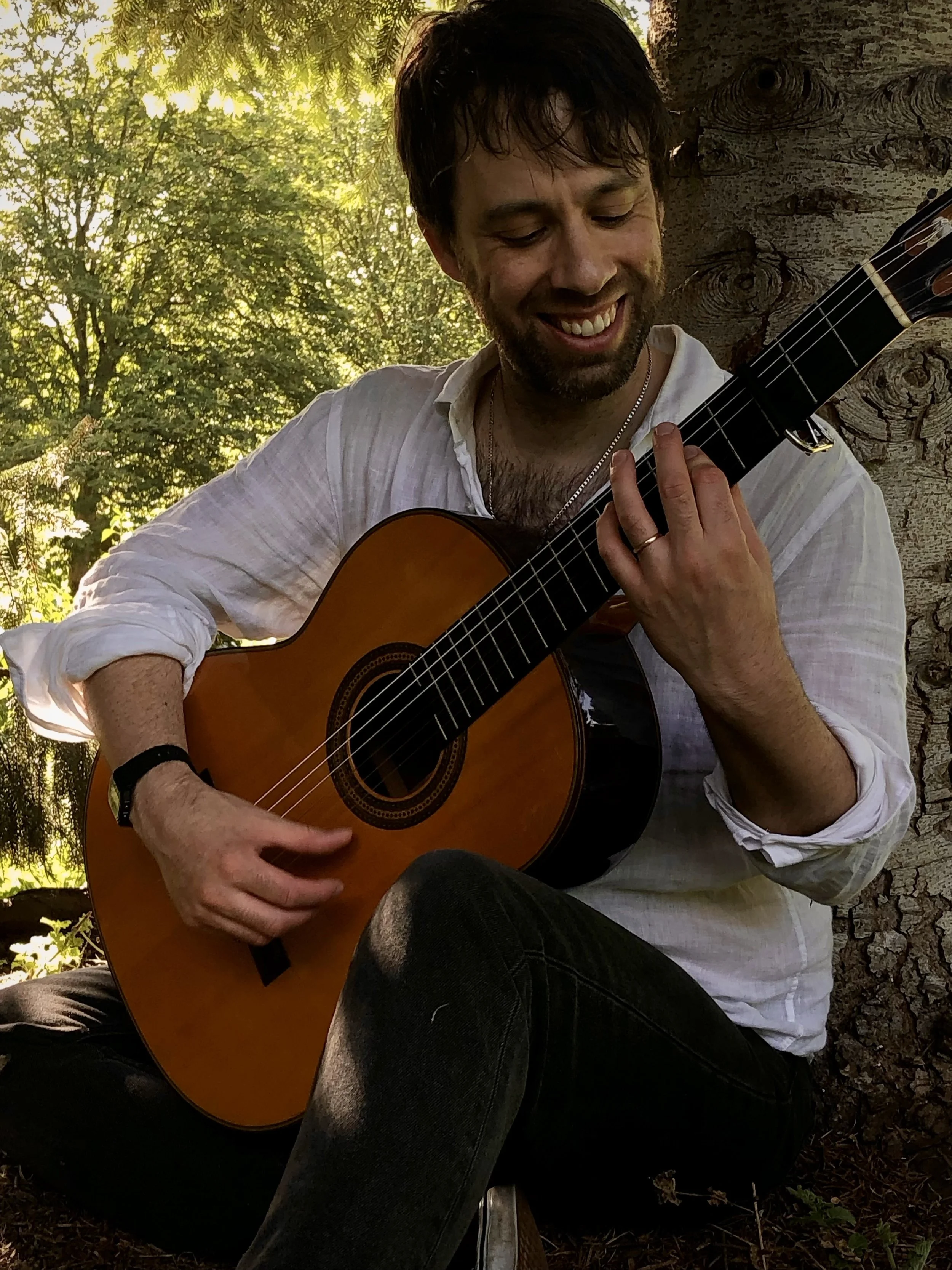 Nicolas Lewis plays his classical guitar under a tree in a York wood