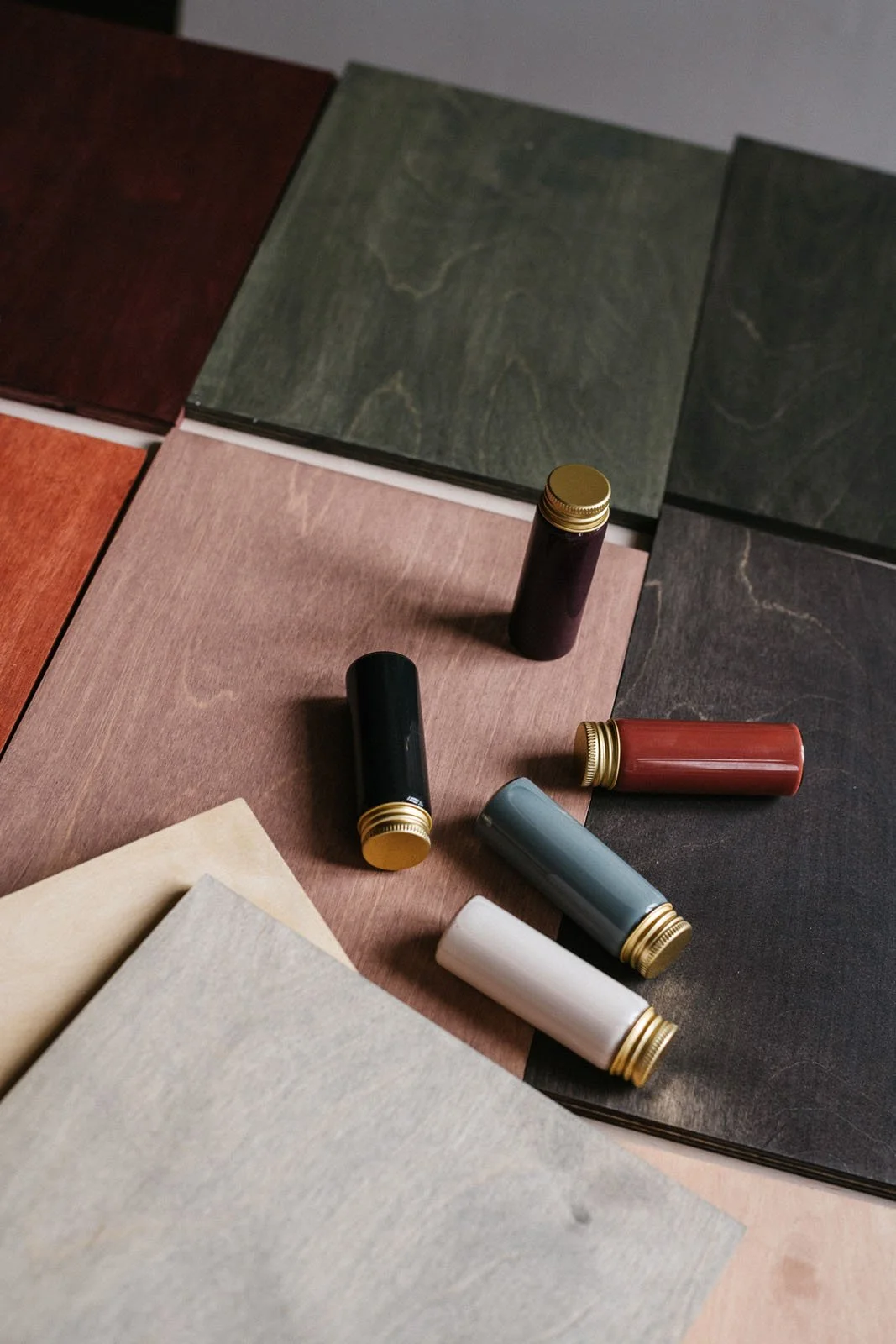 30ml vials containing coloured stains put on top of stained A4 wooden sample boards.