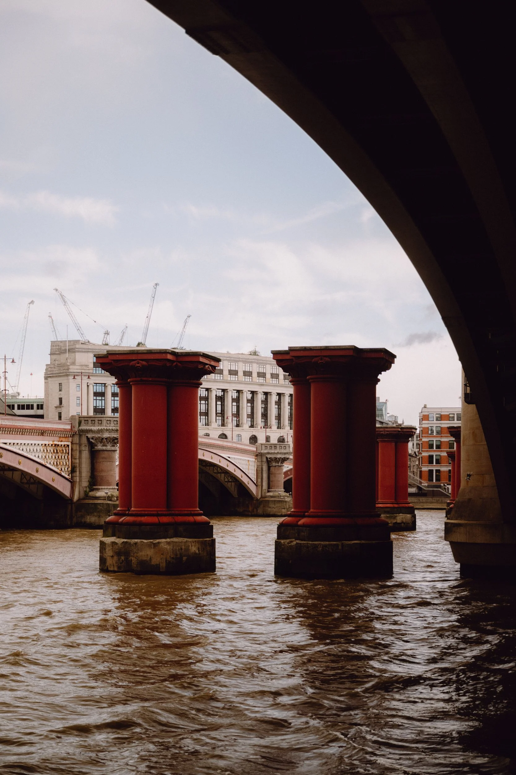 Red pillars on the river Thames, reminiscent of Atelier Ellis' colour Lundenwick.