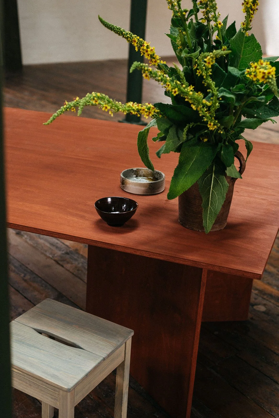 Wood table stained in a warm red coloured stained with wooden stool coloured with light blue stain.