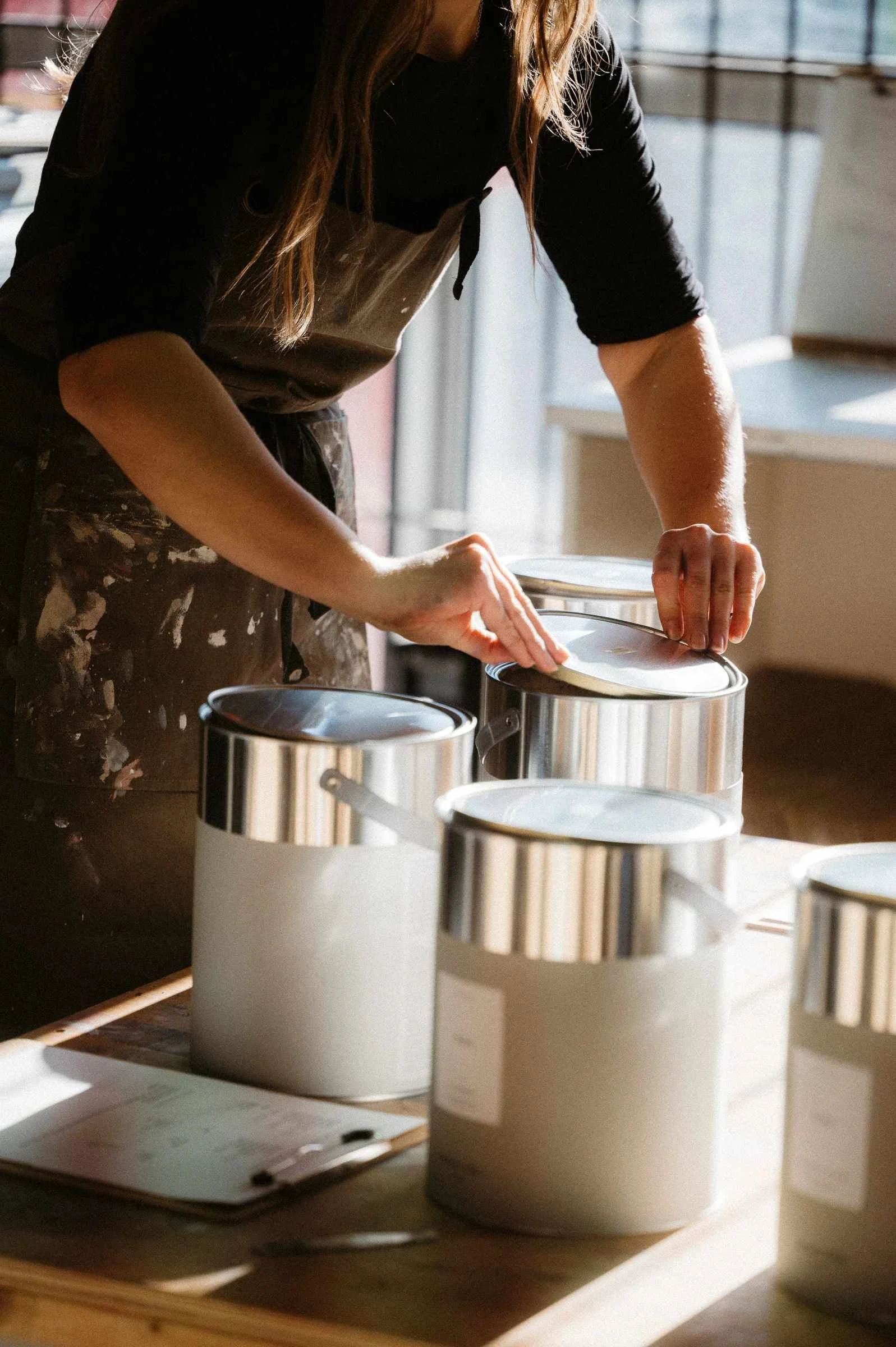 Atelier Ellis employee putting lids on paint tins.