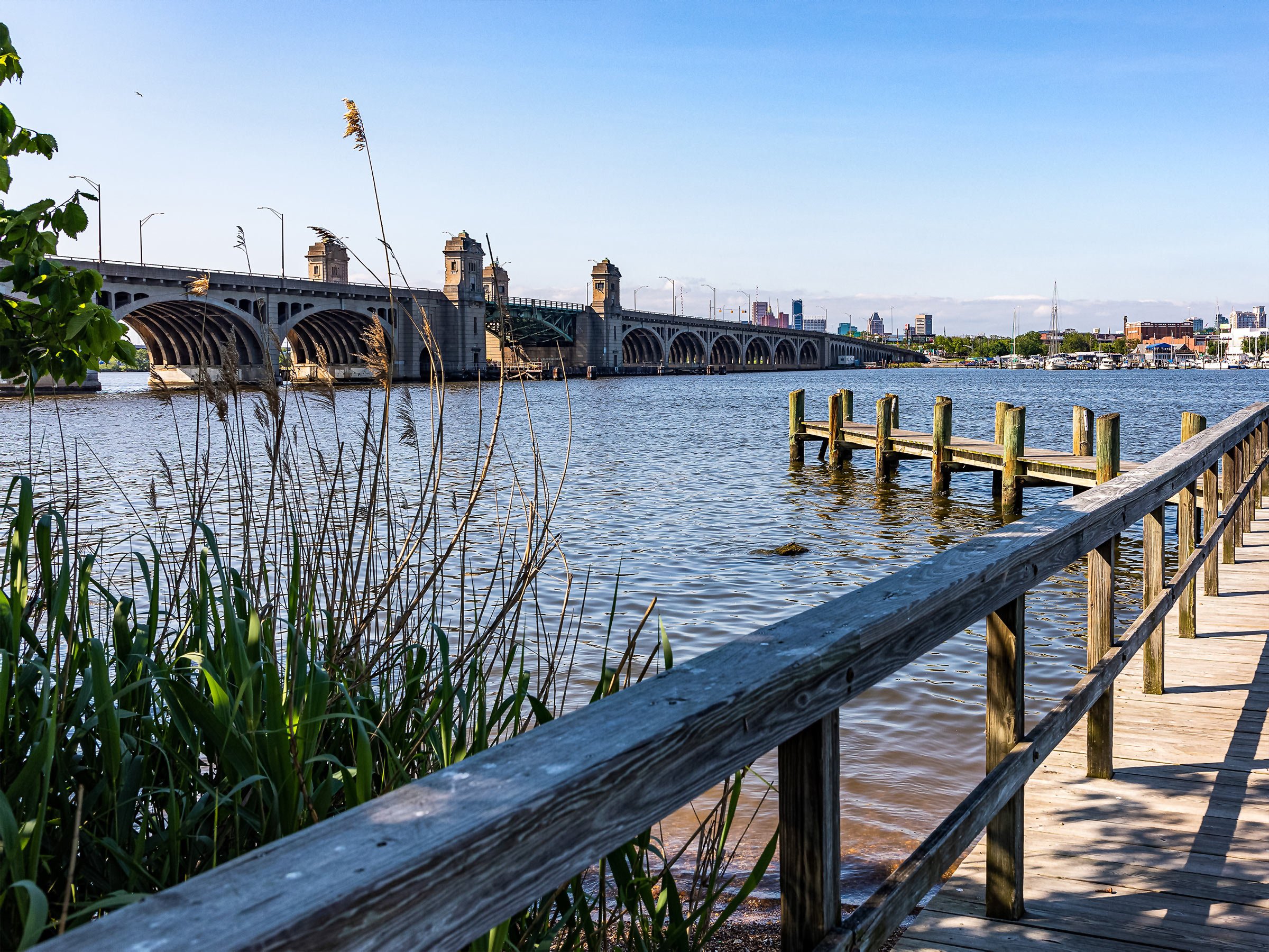  Tranquil wooden dock surround by tall wetland grasses and Hanover ST. Bridge in background 