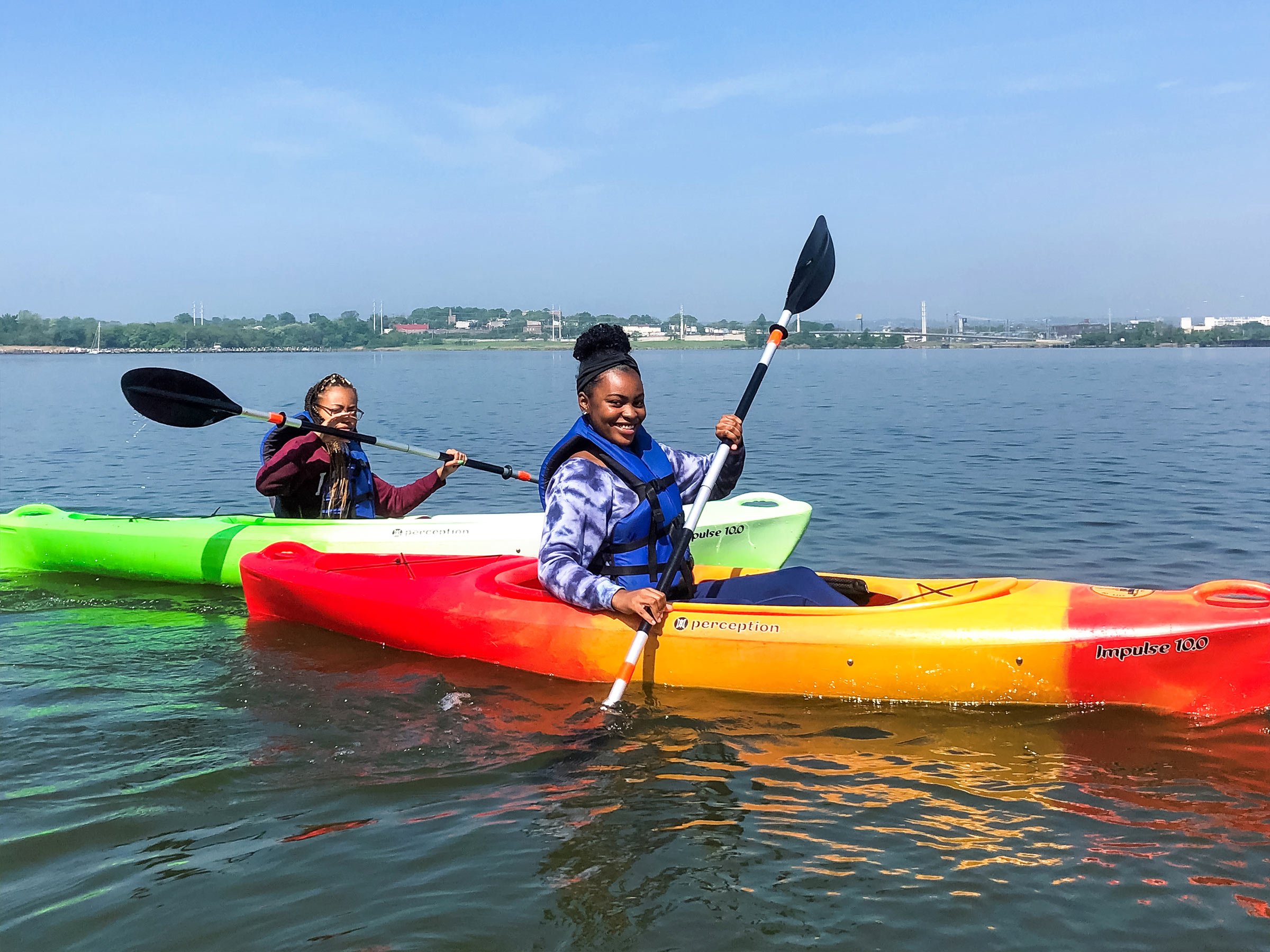  Two smiling young women kayaking in the middle of the harbor 