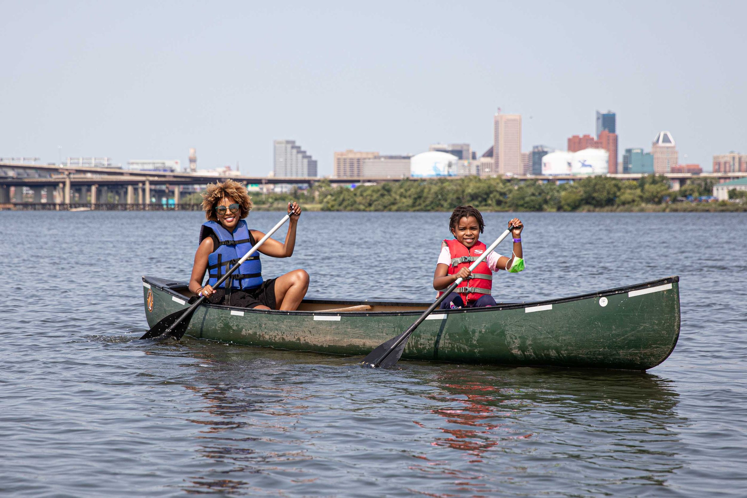  Mother and daughter canoe together in harbor 