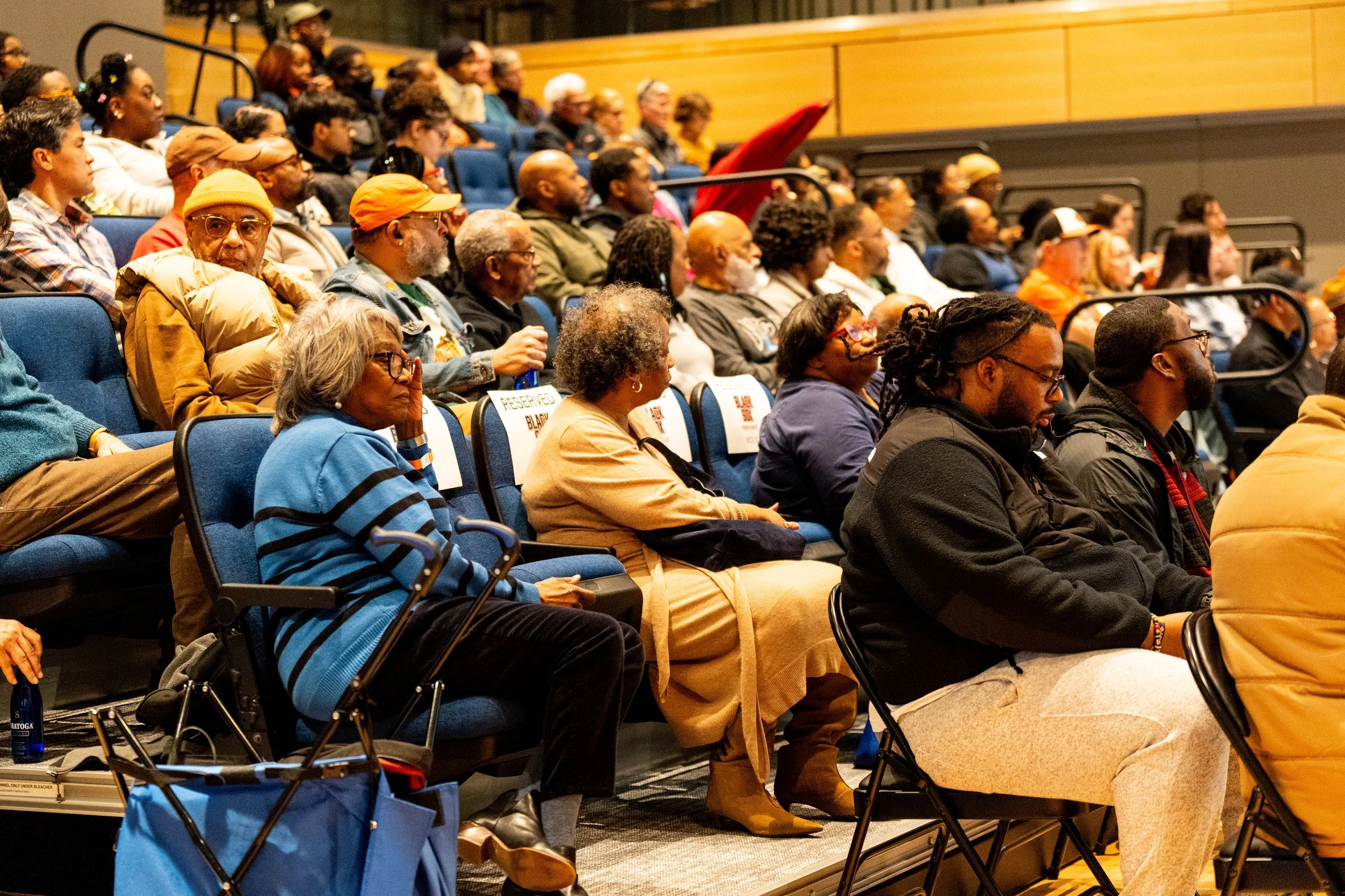  A crowd of people are seated facing the panelist at the event.  