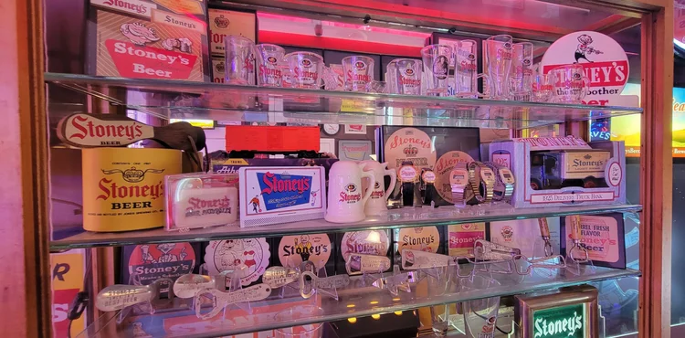 Glass case packed with vintage Stoney's labels, coasters, and cans