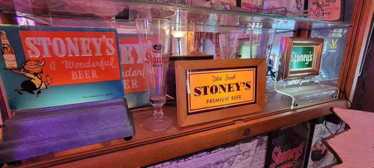 Backlit Stoney's beer signs and glassware on a shelf