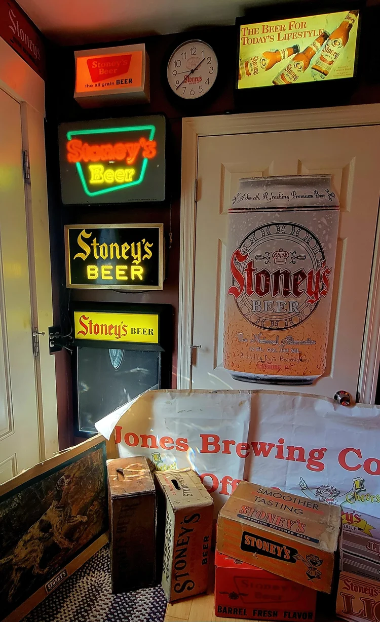 Lit Stoney's Beer signs and a clock in a corner display