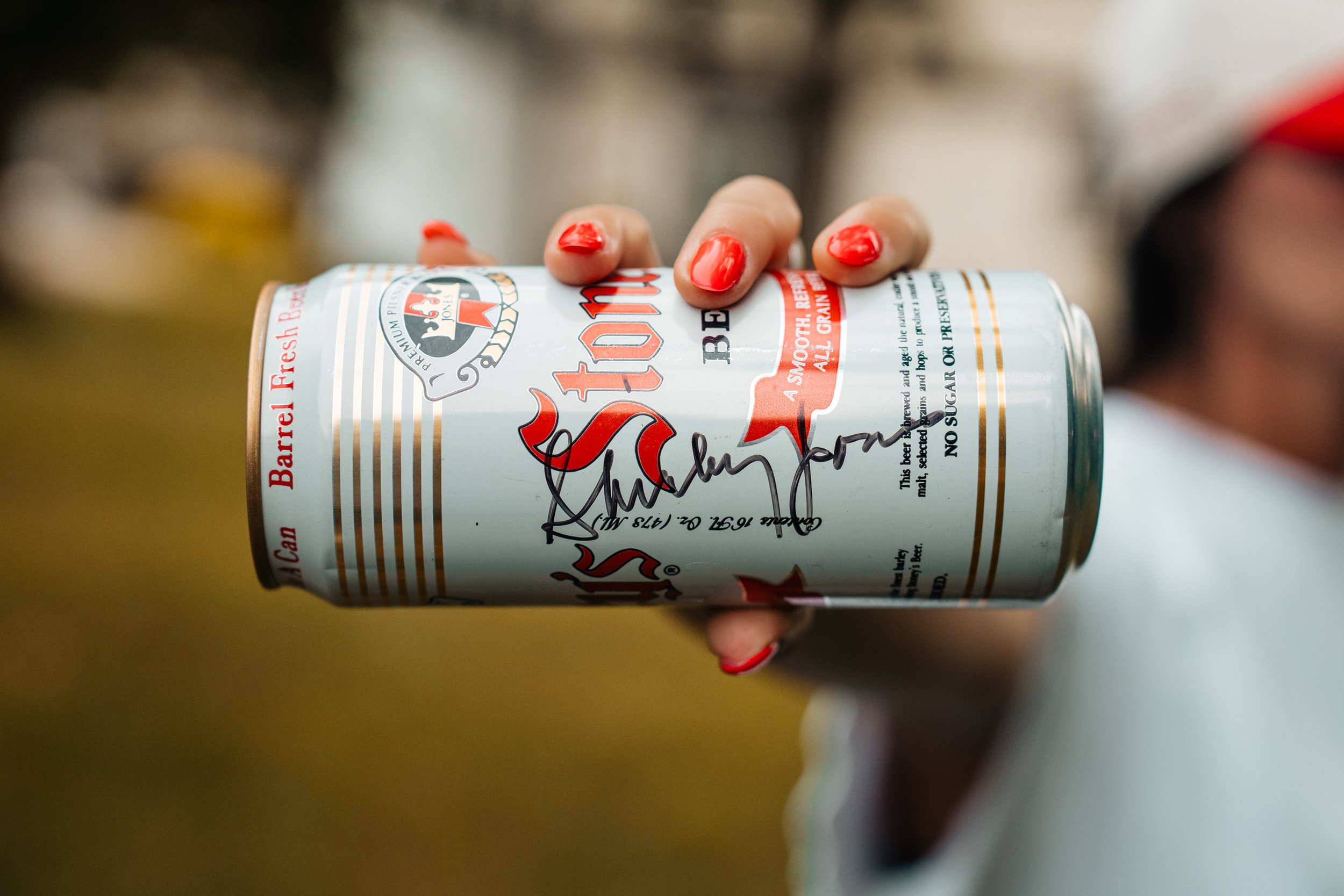 Close-up photo of a vintage Stoney’s Beer can signed by Shirley Jones, held in a hand with red-painted nails. Captured by Pittsburgh-based professional photographer Ian Jones using a Sony a1 and Tamron 28-75mm lens. ISJDESIGNS