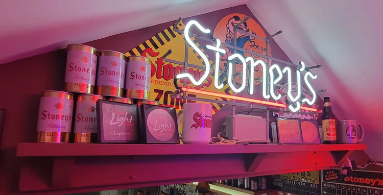 Long shelf of vintage Stoney's cans beneath a lit Stoney's sign