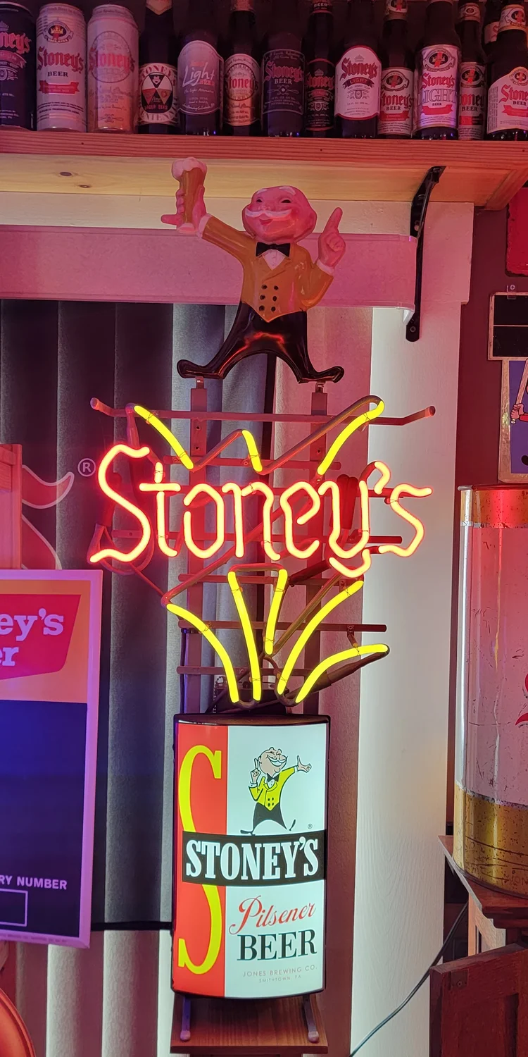 Stoney's Beer neon sign over a column of advertising