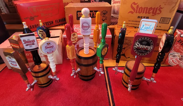 Wooden barrels topped with Stoney's tap handles beside a bottle display