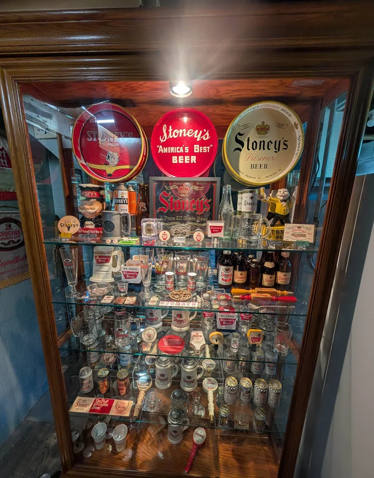 Lit glass cabinet filled with vintage Stoney's Beer cans and memorabilia