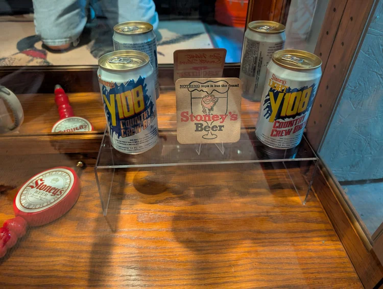 Vintage Stoney's Beer cans with a small Stoney's standee on a glass shelf