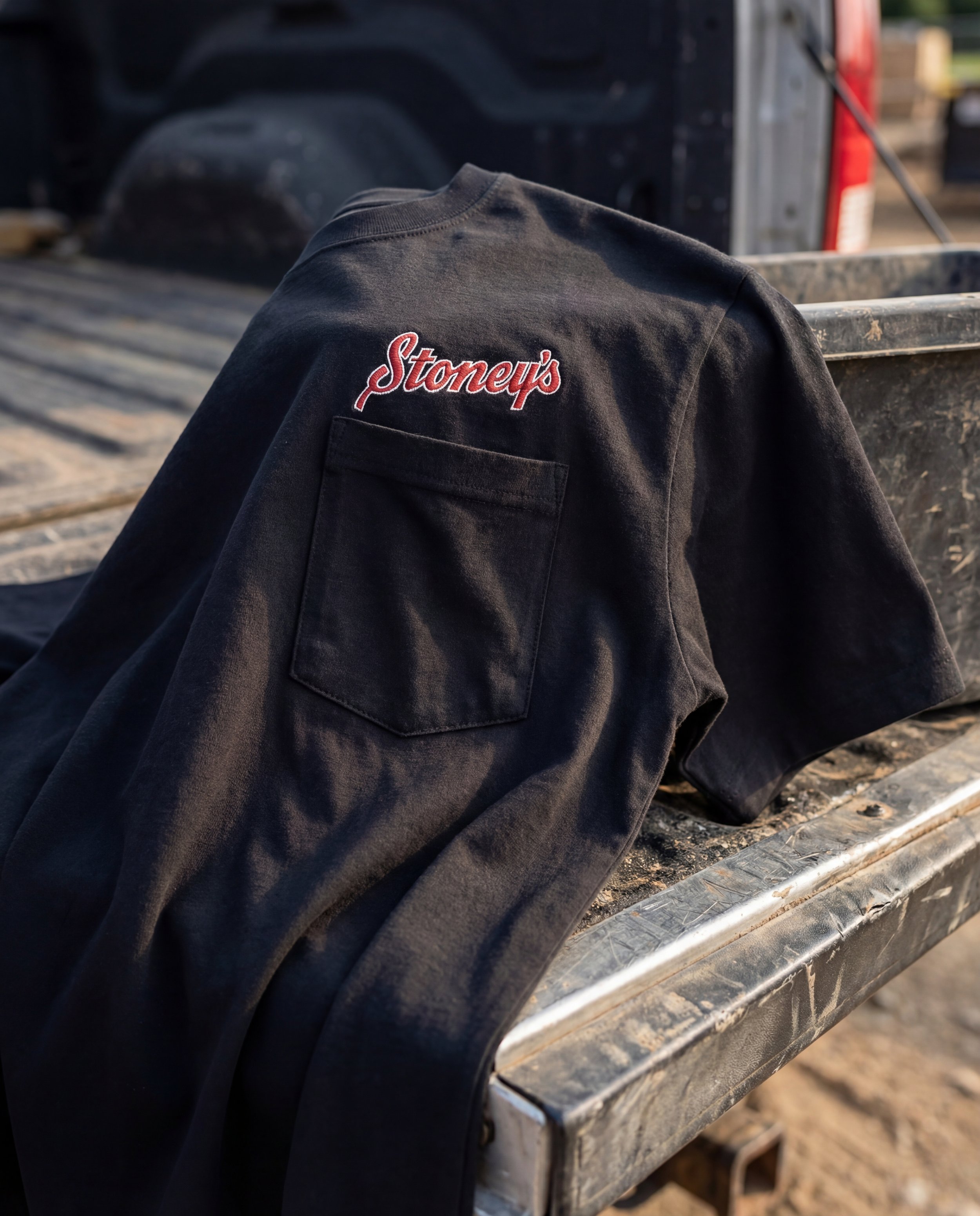 Stoney’s Built To Work black workwear t-shirt with embroidered logo resting on a rugged pickup truck bed in Pennsylvania jobsite setting