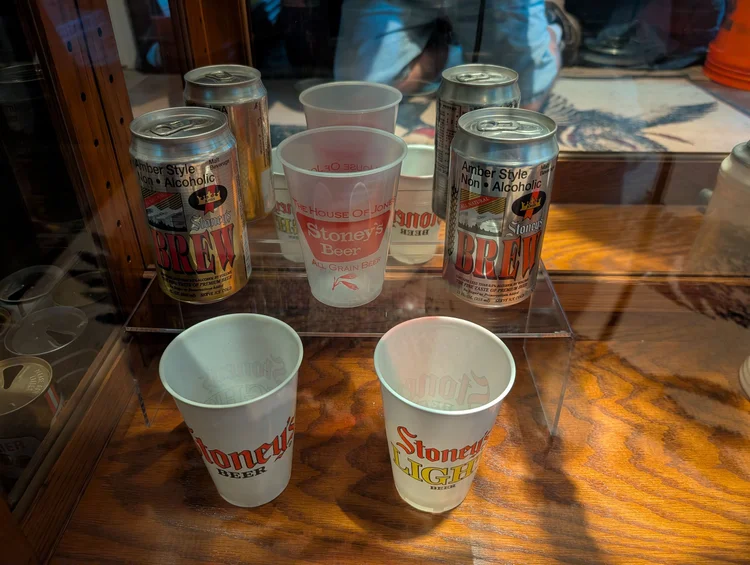 Vintage Stoney's Beer cans and waxed advertising cups on a display shelf
