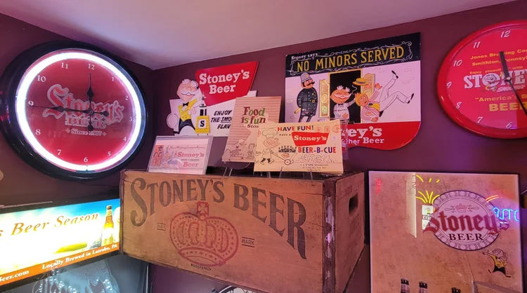 Stoney's Beer neon sign above a wooden crate and a Mr. Smoothie clock
