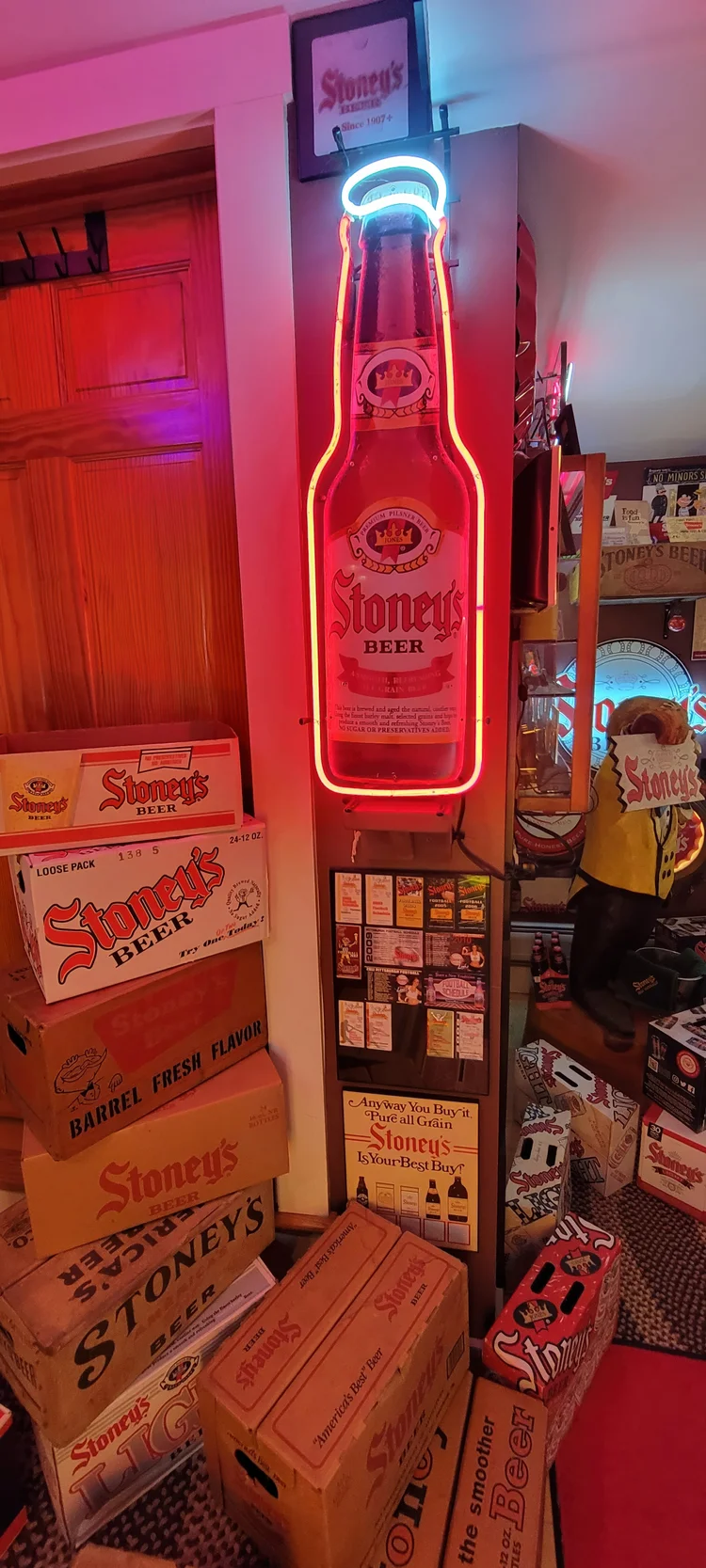 Neon Stoney's bottle sign in a red-lit corner