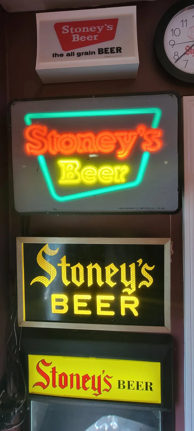 Stacked lit Stoney's Beer signs in a dark corner